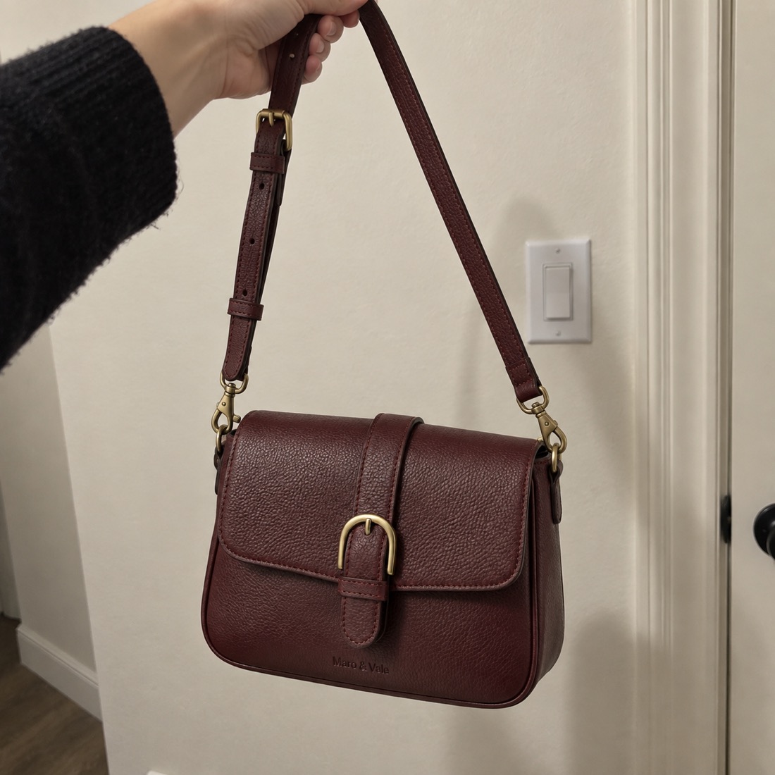 Phone snap of a leather crossbody bag held against a wall
