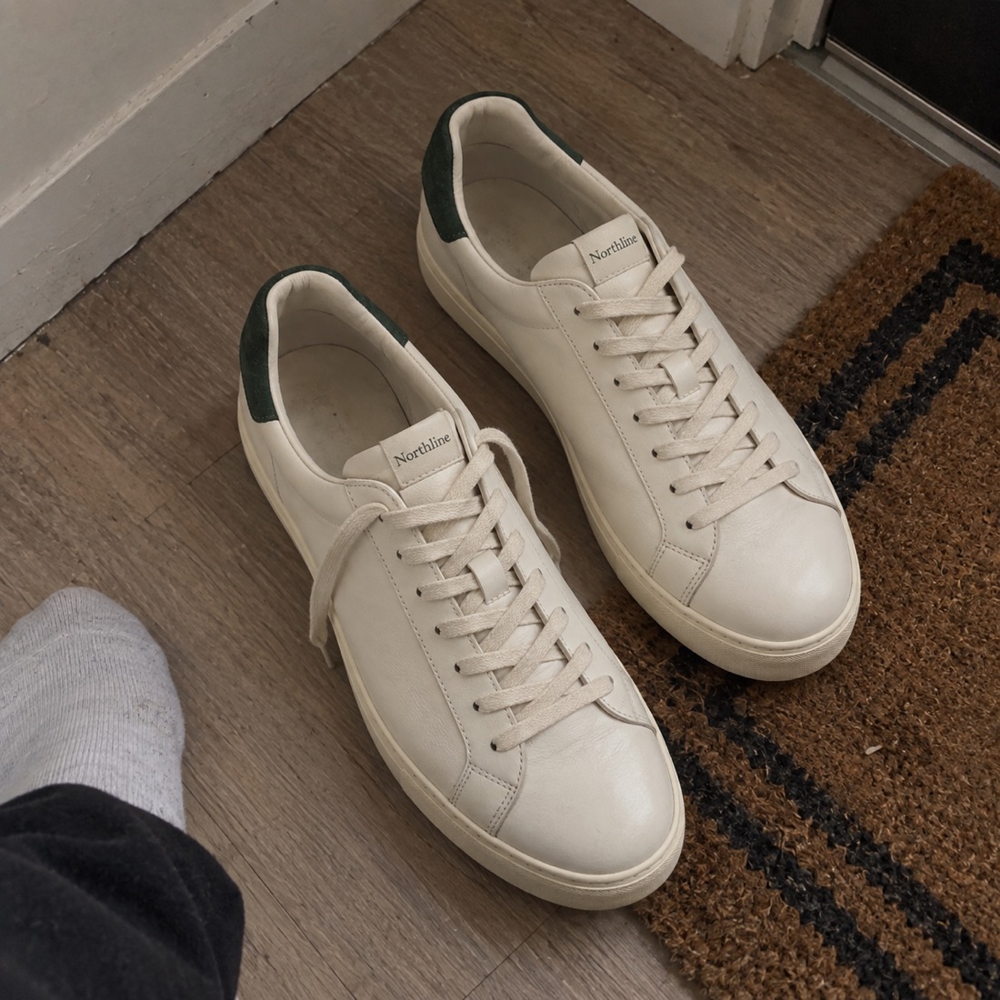 Phone snap of white sneakers on a hallway floor